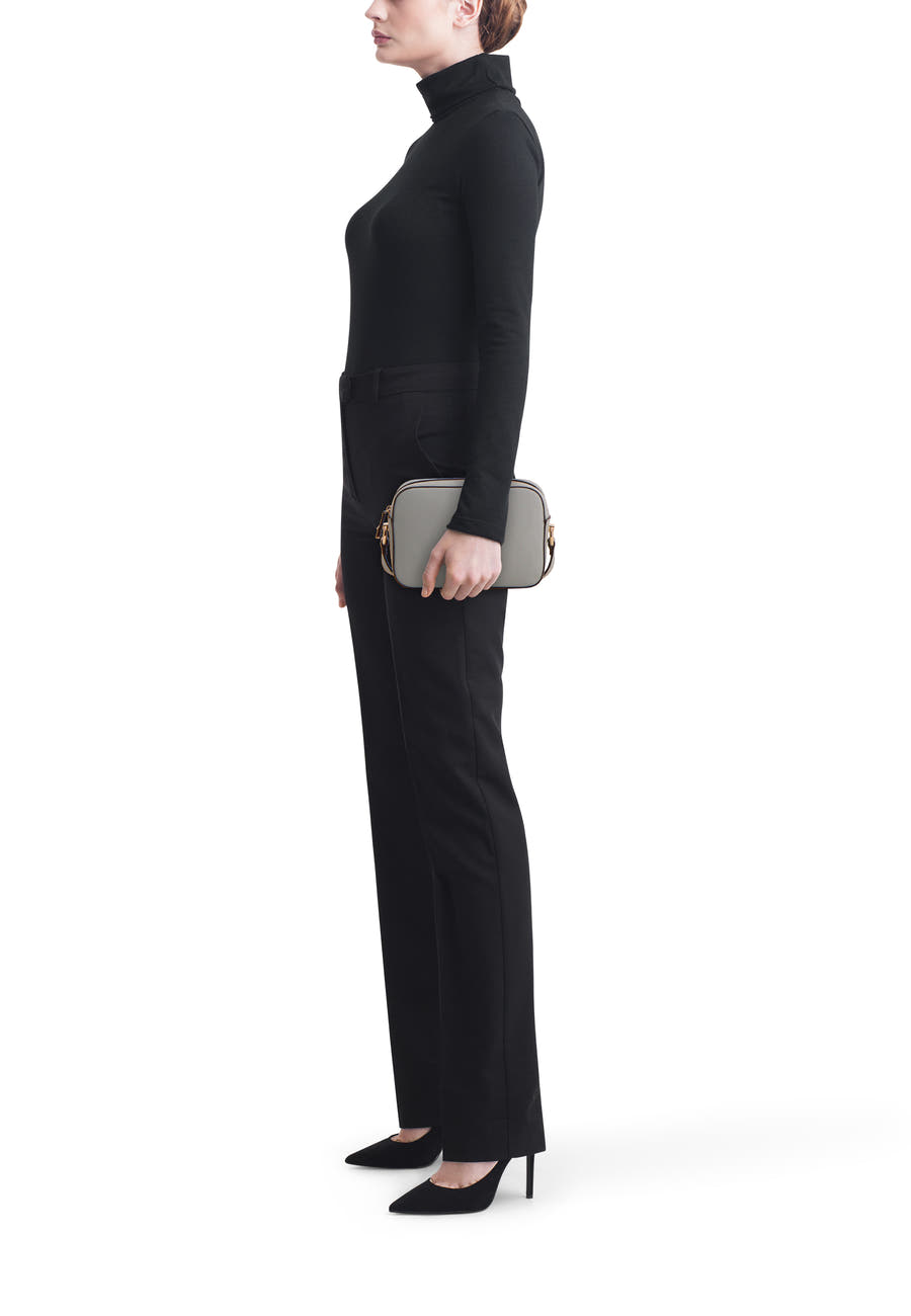 Sac à bandoulière bleu de LIU JO, porté avec un pantalon et un pull noirs, vue de côté.
