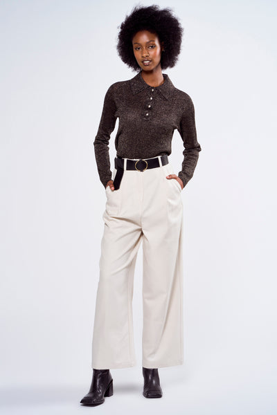 Polo noir par ASTRID Black Label à manches longues, porté avec un pantalon taille haute écru et des bottines noires.
