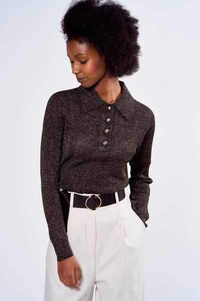 Polo noir à manches longues par ASTRID Black Label, boutonné, porté avec pantalon taille haute et ceinture noire.
