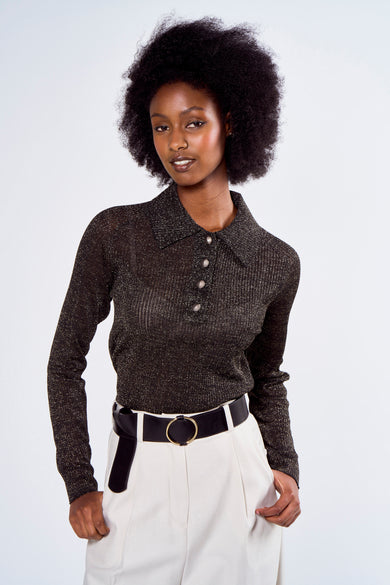 Polo noir scintillant d'Astrid Black Label avec trois boutons, porté avec une ceinture noire et un pantalon taille haute.