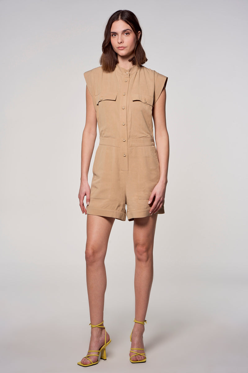 Combi-short beige de ASTRID Black Label, avec col et boutons, porté avec des talons hauts jaunes.
