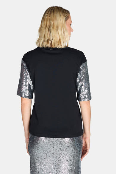 Zwart T-shirt met korte mouwen ARTIGLI, mouwen met zilveren pailletten, gedragen met een bijpassende rok.
