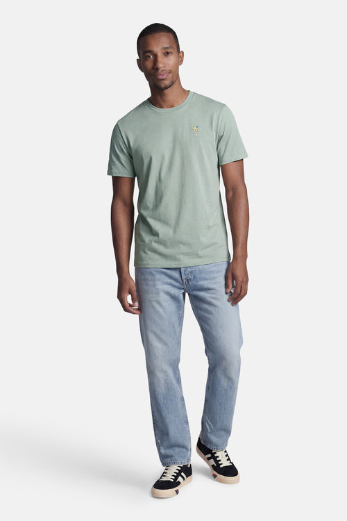 T-shirt vert de STROM à manches courtes avec broderie cocktail sur la poitrine, porté par un homme en jean.