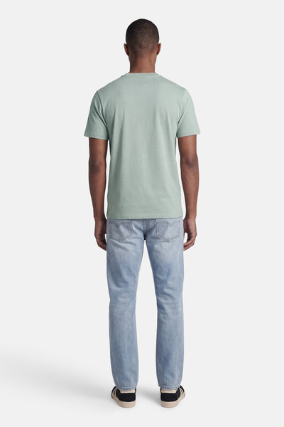 T-shirt vert de STROM à manches courtes, porté de dos avec un jean bleu clair et des baskets.