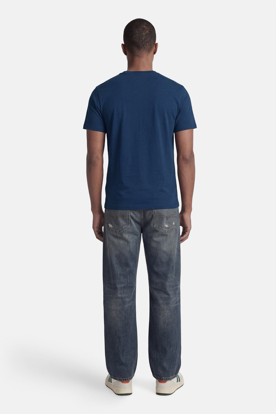 Blauwe STROM T-shirt met korte mouwen, van achteren gedragen met een verbleekte spijkerbroek en sneakers.