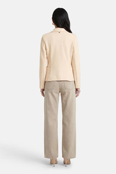 Blazer beige d'AMELIE ET AMELIE, porté avec un jean et des escarpins assortis, vue de dos.
