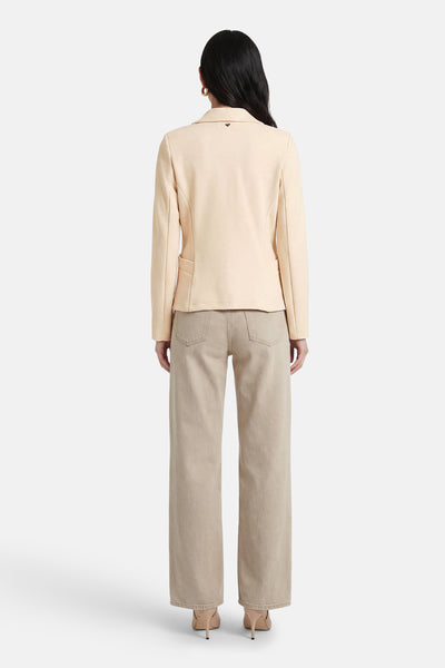 Beige blazer van AMELIE ET AMELIE, gedragen met een spijkerbroek en bijpassende pumps, van achteren gezien.