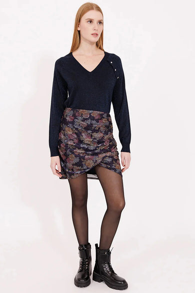 Jupe multicolore de NAF NAF avec motif floral, coupe portefeuille et portée avec des collants noirs et des bottes.
