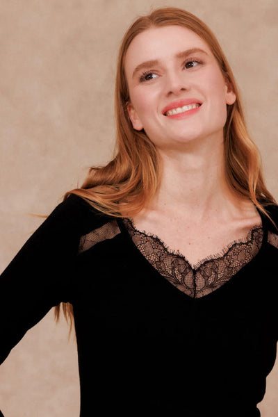 Black long-sleeve t-shirt with lace V-neck and shoulder cutouts, worn by model in lifestyle front view