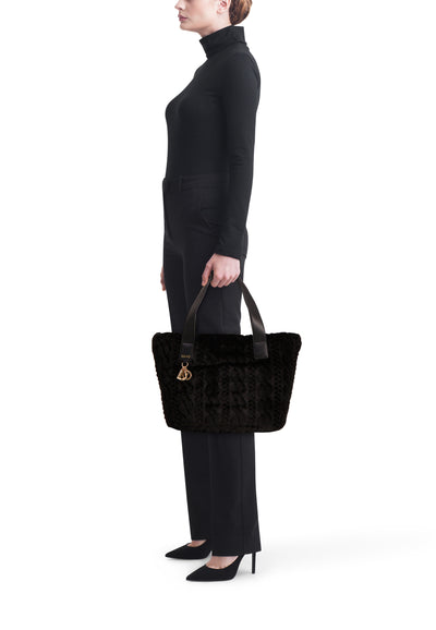 Zwarte schoudertas van imitatiebont van Liu Jo, gedragen met een zwarte trui en broek.