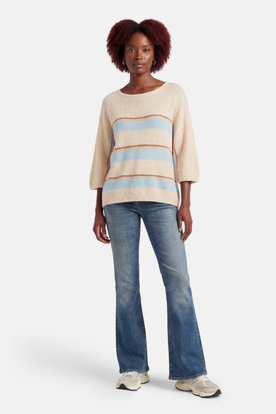 Multigekleurde coltrui van AMELIE ET AMELIE, met blauwe en bruine strepen, gedragen met een uitlopende jeans en sneakers.