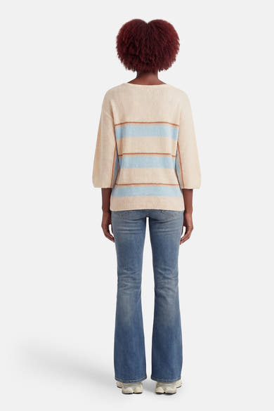 Multikleuren rondehals trui van AMELIE ET AMELIE met blauwe en bruine horizontale strepen, gedragen met een uitlopende blauwe jeans.