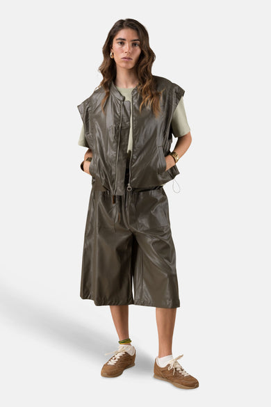 Gilet kaki ADORE porté sur un t-shirt vert pâle avec un short assorti et des baskets marron.
