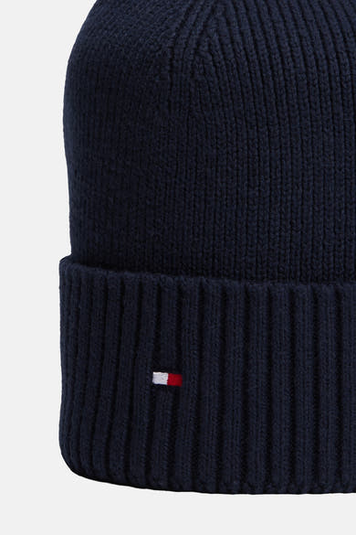 Gros plan sur un bonnet bleu marine TOMMY JEANS en maille côtelée avec revers et petit drapeau brodé.