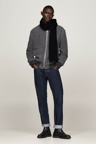 Zwarte geribbelde gebreide sjaal van TOMMY JEANS, gedragen met een grijze jas en een spijkerbroek.