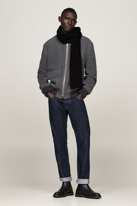 Zwarte geribbelde gebreide sjaal van TOMMY JEANS, gedragen met een grijze jas en een spijkerbroek.
