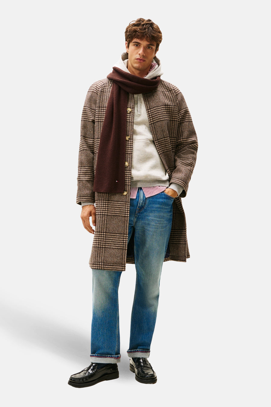 Écharpe brune TOMMY JEANS, tricotée, portée avec un manteau à carreaux, un sweat à capuche et un jean.