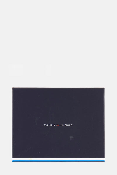 Zwarte TOMMY JEANS portemonnee, op een marineblauwe achtergrond, met merklogo.