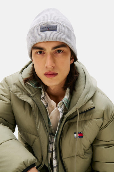 Bonnet gris chiné de Tommy Jeans, porté avec une veste matelassée vert olive à capuche.