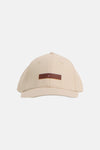 Casquette beige de TOMMY JEANS, avec une étiquette marron ornée du logo.