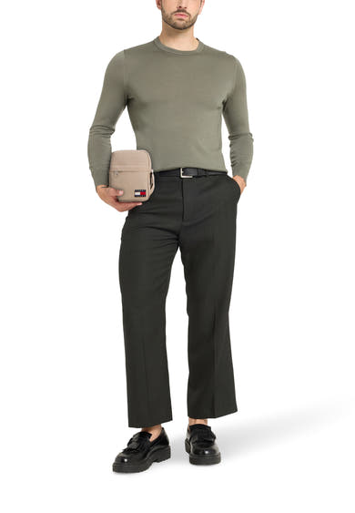 Sac à bandoulière beige de TOMMY JEANS, porté par un homme en pantalon et mocassins noirs.