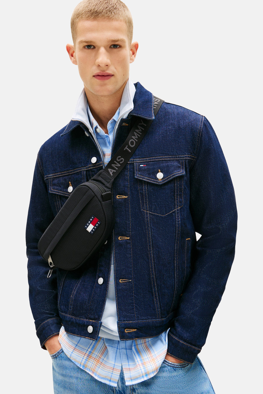 Zwarte schoudertas van Tommy Jeans met een logoband en gedragen met een blauwe spijkerjas.