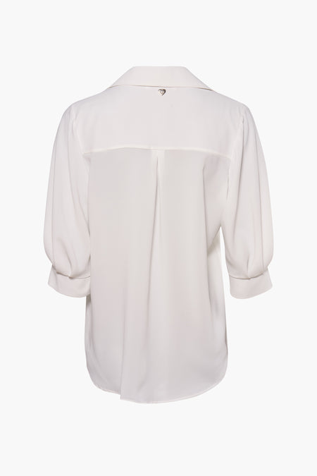 Chemisier blanc à manches trois-quarts par AMELIE ET AMELIE, avec plis au dos et détail cœur argenté.