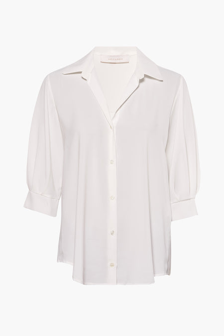 Chemise à manches longues blanche d'Amélie et Amélie, avec une fermeture boutonnée et des manches 3/4 bouffantes.
