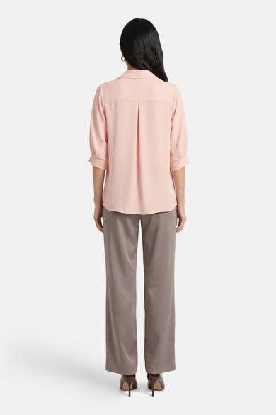 Roze blouse met korte mouwen van AMELIE ET AMELIE, met plooien aan de achterkant en gedragen met een grijze broek.