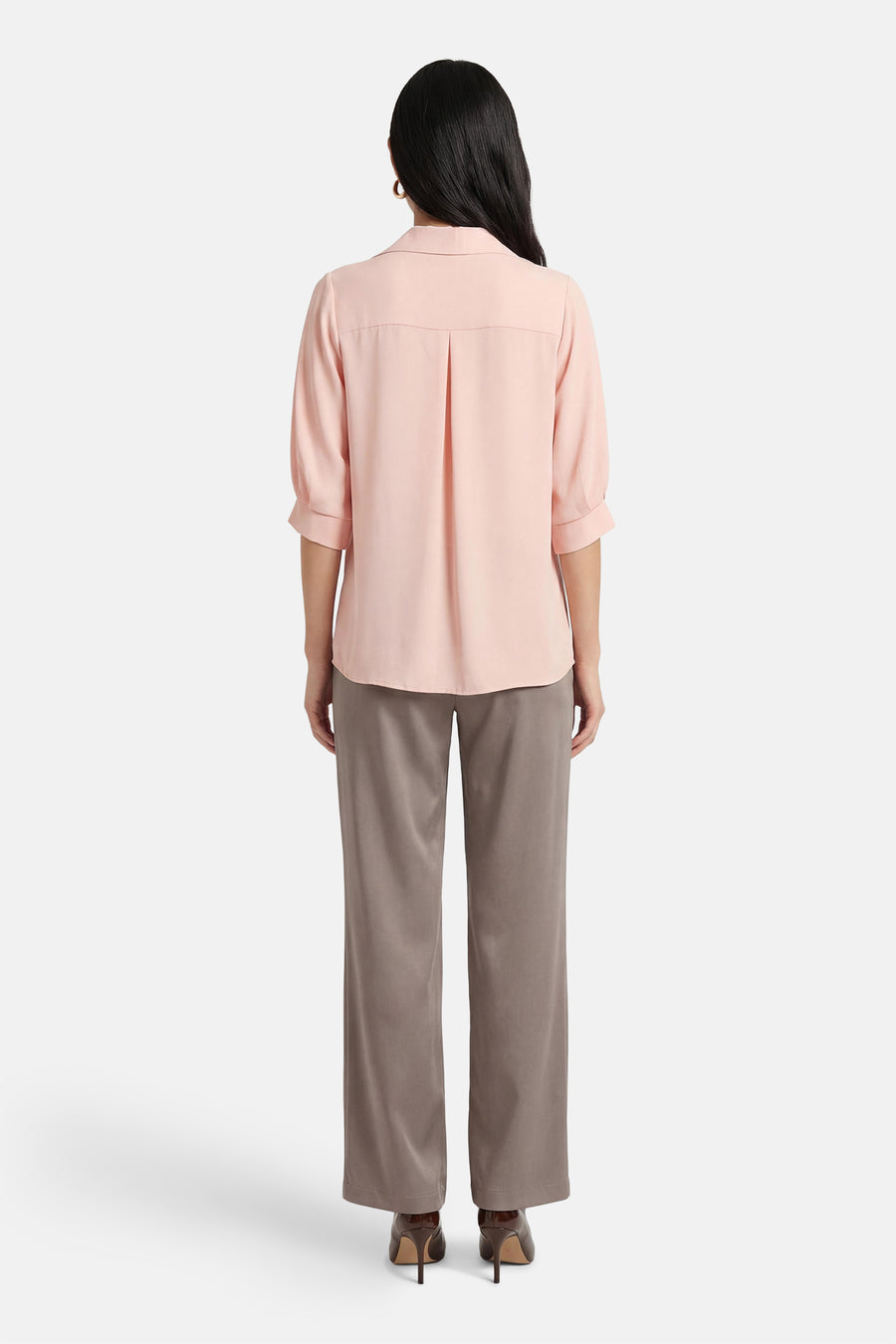 Roze blouse met korte mouwen van AMELIE ET AMELIE, met plooien aan de achterkant en gedragen met een grijze broek.