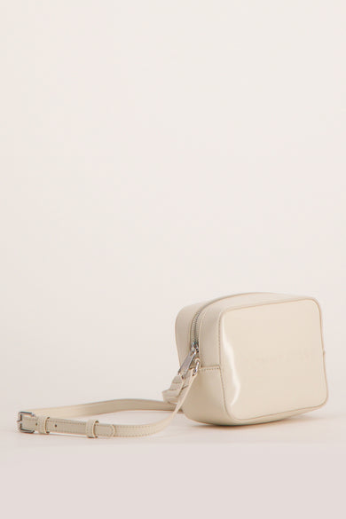 Sac à bandoulière écru de Tommy Jeans, avec une bandoulière réglable et fermeture zippée argentée.
