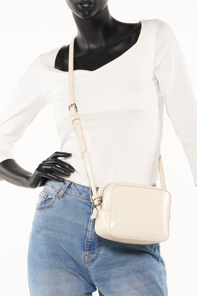 Ecru schoudertas van TOMMY JEANS gedragen door een model met een blauwe jeans en een witte top.