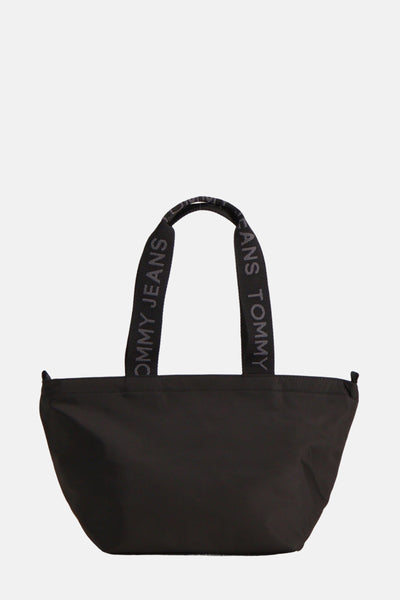 Sac bandoulière noir de Tommy Jeans, avec anses logotypées « Tommy Jeans » sur fond blanc.