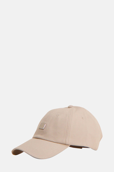 Beige pet van TOMMY JEANS, met een zilveren plaat aan de voorkant en een keperbinding textuur.