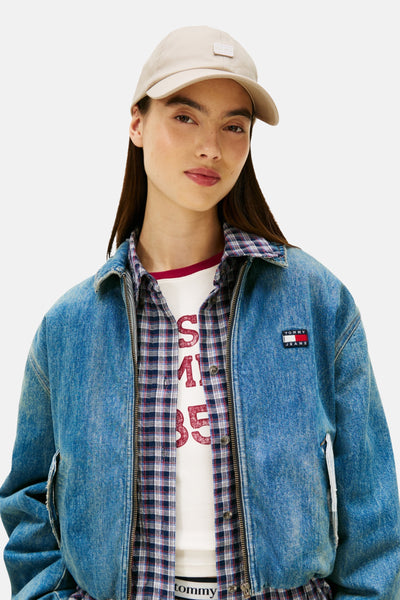Beige pet van TOMMY JEANS, gedragen met een spijkerjasje en een geruit overhemd.