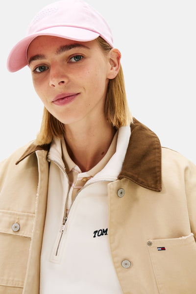 Roze pet van TOMMY JEANS, gedragen door een model met een beige jas met bruine kraag.