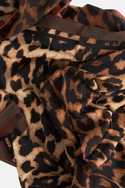 Foulard brun de Guess, motif léopard et bordures à rayures rouges, disposé en plis.
