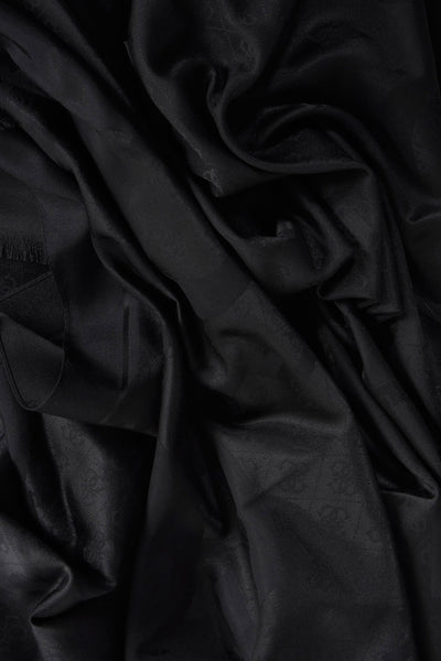 Zwarte Guess® sjaal met een ton-sur-ton patroon, voorzien van een gedrapeerde textuur en een kwastdetail aan één kant.