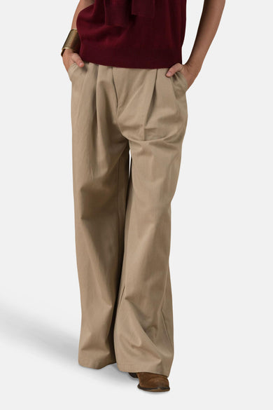 Chino beige de ADORE, pantalon ample avec des plis, porté avec un pull bordeaux et des chaussures marron.