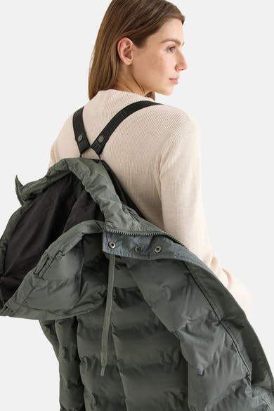 Veste longue vert de CECIL, portée avec un pull beige, bretelles noires apparentes.