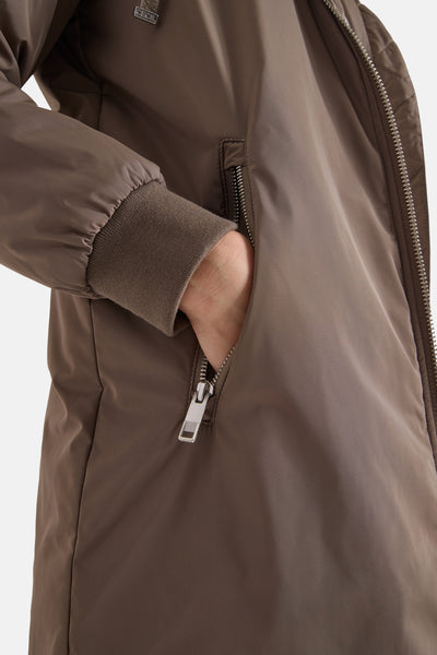 Veste longue marron de CECIL, avec une fermeture éclair argentée et une main dans la poche.