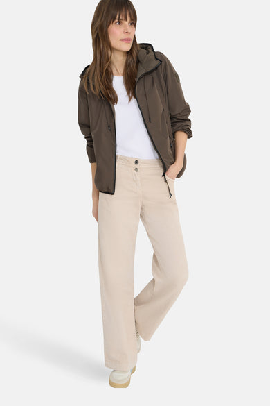 Veste courte brune de CECIL, portée avec un t-shirt blanc et un pantalon beige à jambes larges.