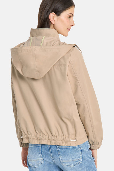 Veste courte beige de CECIL, avec capuche et cordon de serrage à la taille, portée avec un jean.

