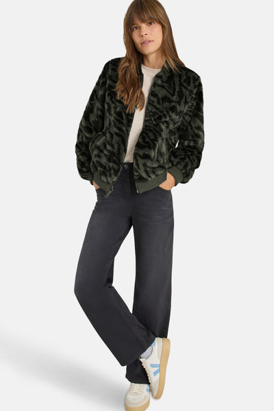 Veste courte verte à motifs zébrés de CECIL, portée avec un jean noir à jambes larges et des baskets blanches.
