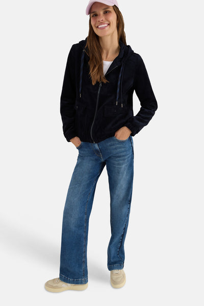 Korte blauwe corduroy jas van CECIL, gedragen met een blauwe jeans en een roze pet.