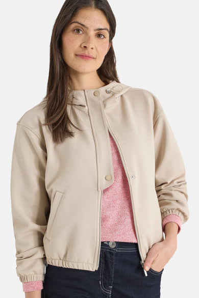 Gilet beige de CECIL avec fermeture éclair et détails à boutons, porté sur un pull rose et un jean foncé.