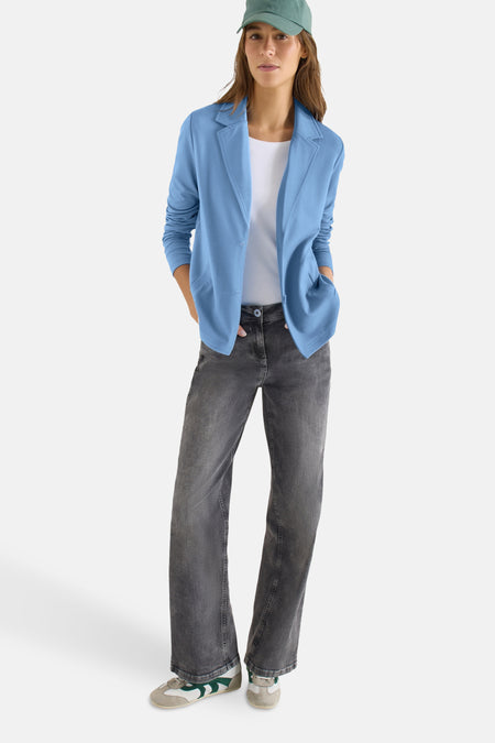 Blazer bleu de CECIL, porté avec un t-shirt blanc, un jean gris foncé et une casquette turquoise.
