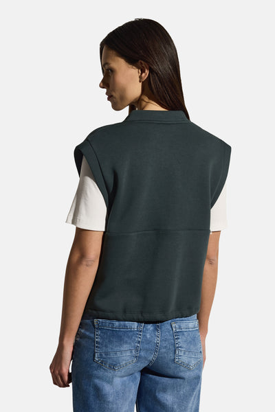 Groen vest van CECIL, gedragen over een wit T-shirt, met een blauwe jeans.