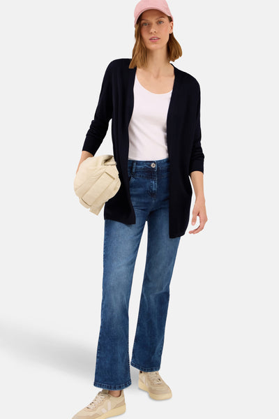 Blauwe CECIL-gilet, gedragen over een eenvoudig wit T-shirt, met een high-waist jeans en een beige tas.