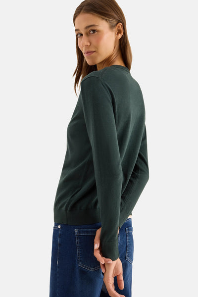 Groene CECIL-cardigan, gedragen met een spijkerbroek, handen gekruist achter de rug.